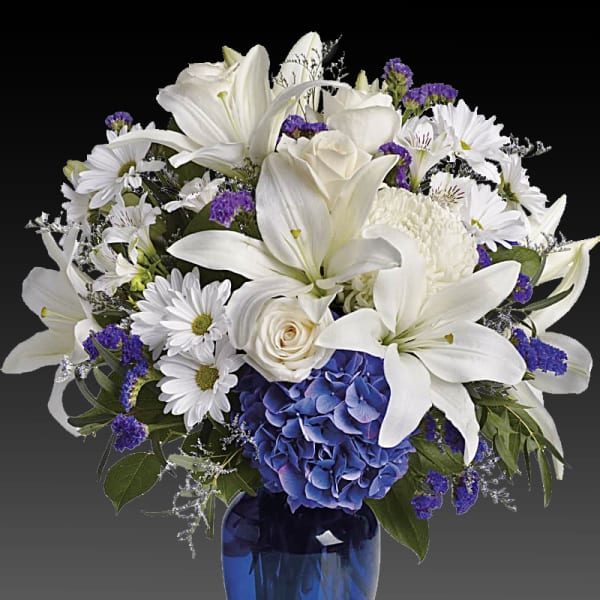 White lilies and daisies with blue hydrangea in a blue vase