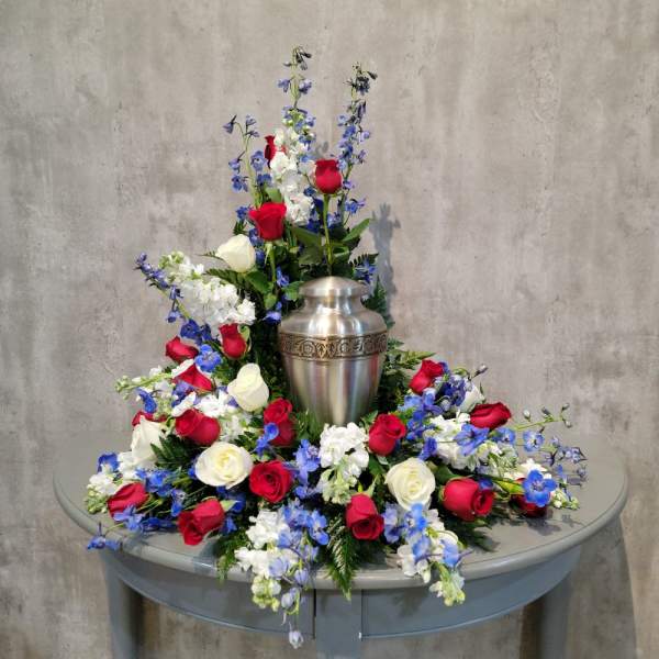 Red, white, and blue floral arrangement around a silver urn