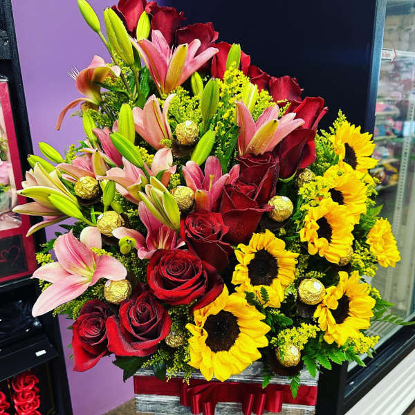 Mixed bouquet with red roses, pink lilies, and yellow sunflowers in a box