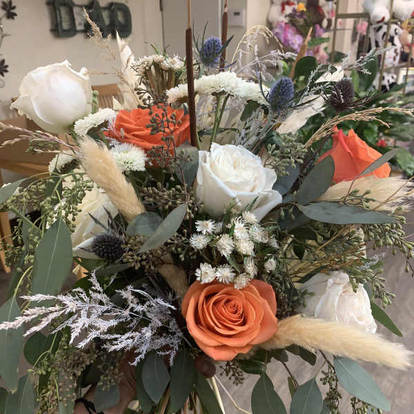 Hand-tied bouquet of orange and white roses with dried grasses