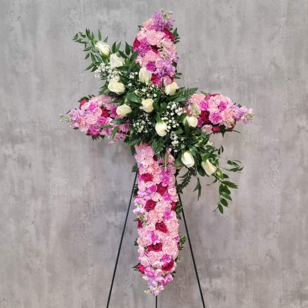 Large floral cross on a stand with pink and white roses