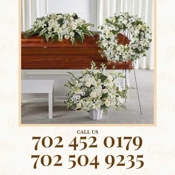 White funeral floral arrangements with a casket spray and standing wreath.