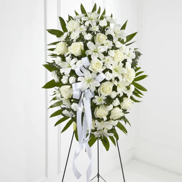 White floral standing spray with roses and lilies on an easel