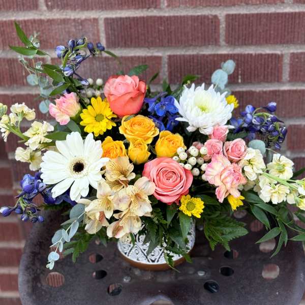 Mixed bouquet of roses, daisies, and white chrysanthemums in a decorative vase