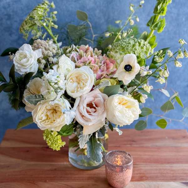 White and blush roses in a glass vase with airy greenery