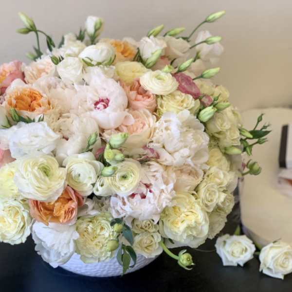 Large pastel bouquet of roses and ranunculus in a white basket