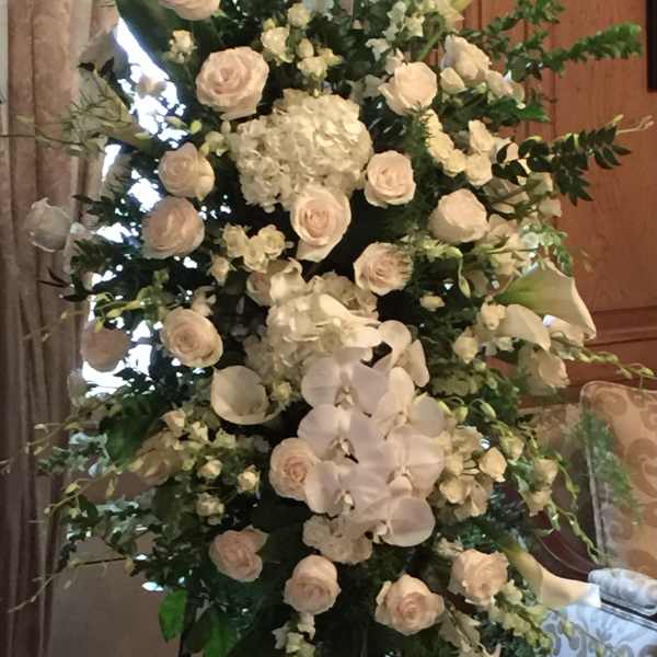 Tall white floral standing arrangement with roses, orchids, and calla lilies