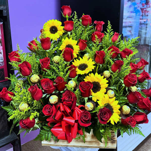 Large bouquet of red roses and yellow sunflowers in a wooden box with a red bow