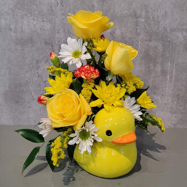 Yellow floral arrangement in a duck-shaped ceramic container