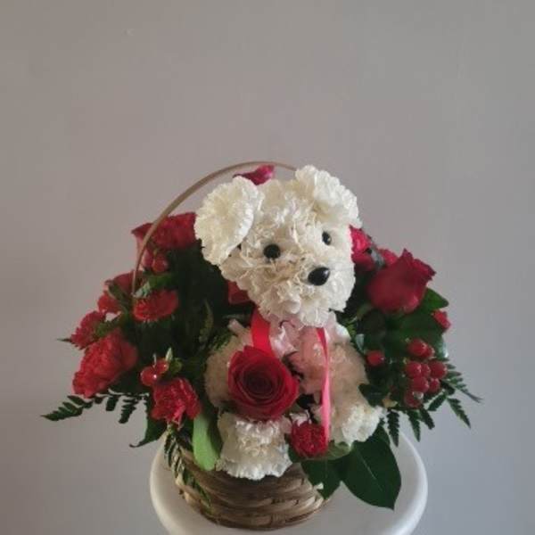 Basket arrangement with a white plush dog and red roses