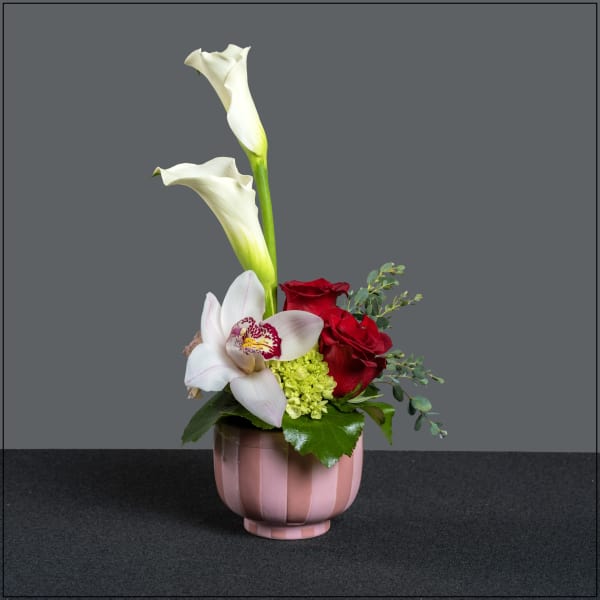 Pink vase with white calla lilies, red roses, and a white orchid