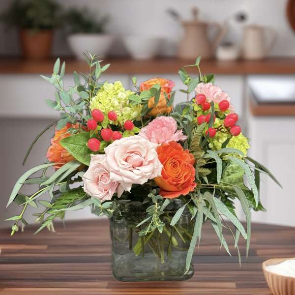 Mixed bouquet of pink and orange roses in a square glass vase