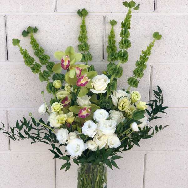 White and pale green floral arrangement in a clear glass vase
