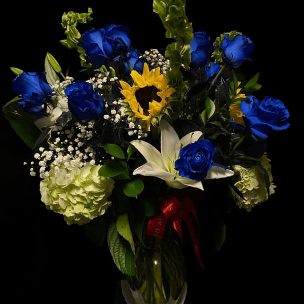 Blue roses and a sunflower in a glass vase