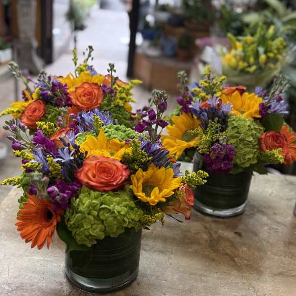Bright mixed flower arrangements in dark glass vases