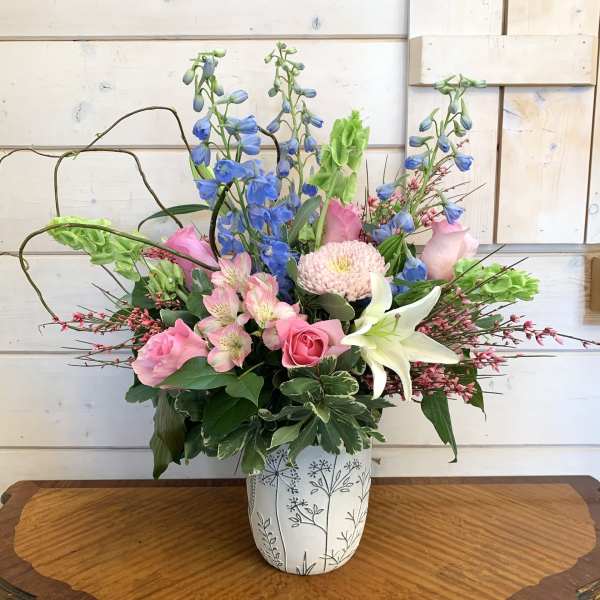 Mixed bouquet in a white patterned vase with pink, blue, and white flowers