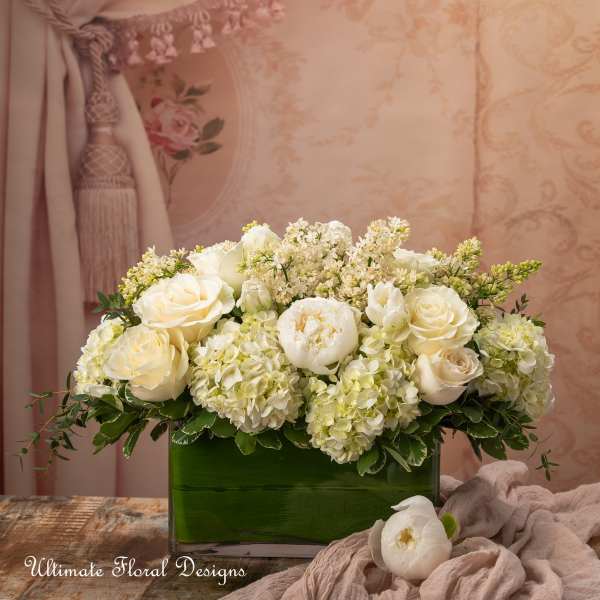 White roses and hydrangeas arranged in a green rectangular vase