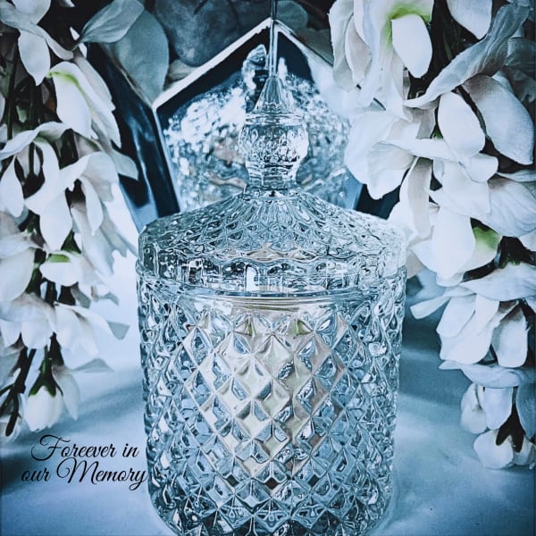 Glass memorial urn surrounded by white flowers
