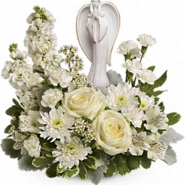 White floral arrangement with roses and daisies around an angel figurine