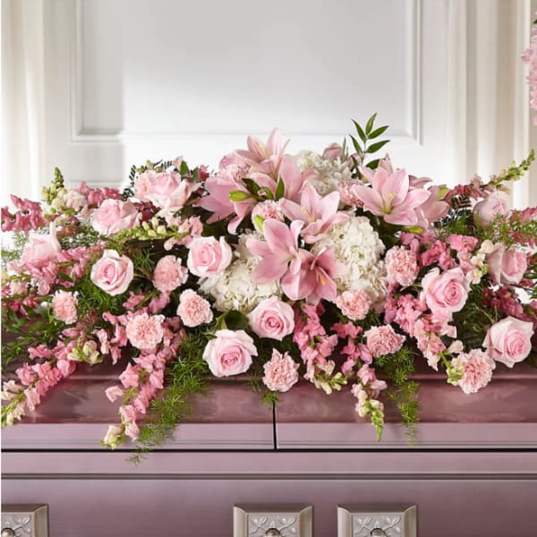 Pink roses and lilies arranged across a casket