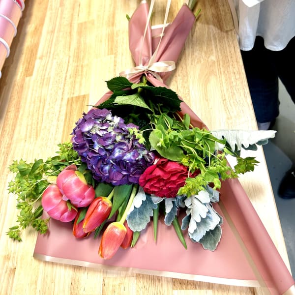 Bouquet of purple hydrangea, pink tulips, and a red rose wrapped in pink paper