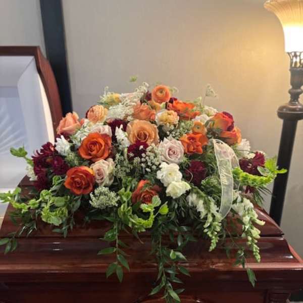Large floral spray on a casket with orange and white roses