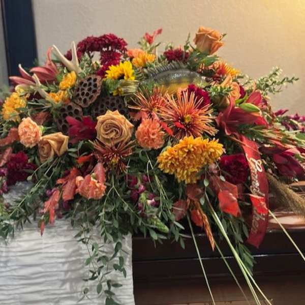 Large casket spray with orange, red, and yellow flowers