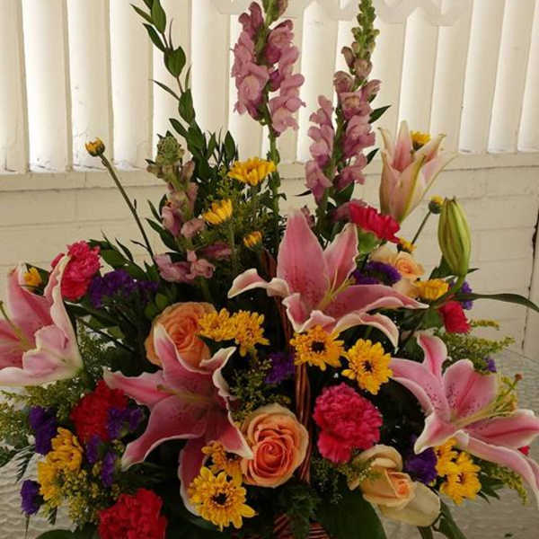 Mixed bouquet with pink lilies, roses, and yellow daisies in a basket