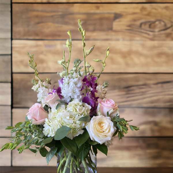 Pink and white roses with purple orchids in a glass vase