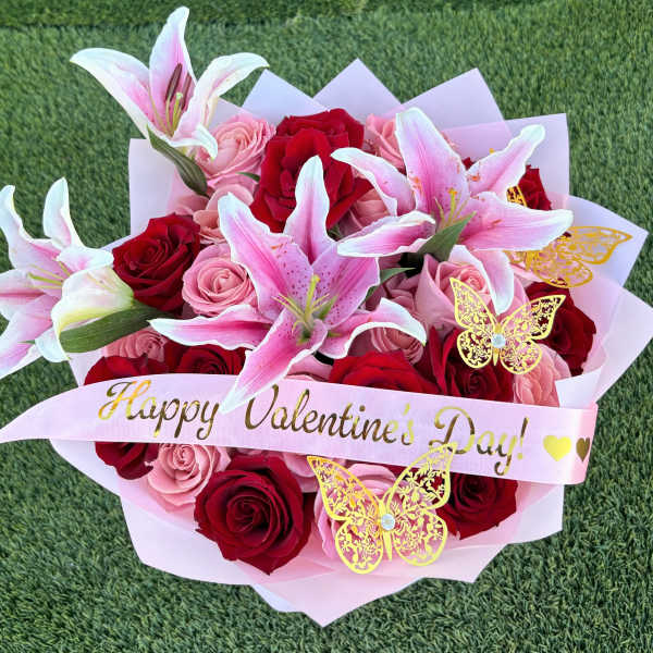 Bouquet of red and pink roses with pink lilies and a Valentine ribbon