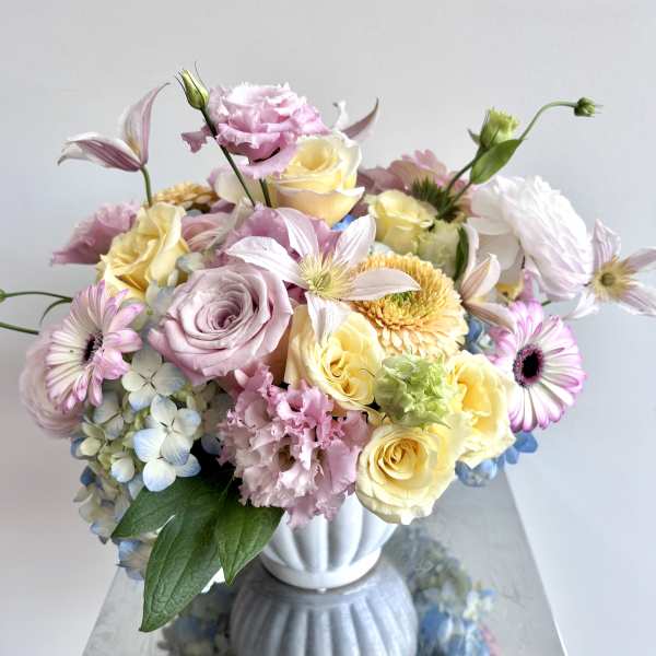 Pastel bouquet of roses, daisies, hydrangea, and lisianthus in a white vase