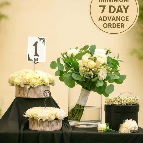 White rose wedding bouquet with matching centerpieces and floral crown on a black-draped table
