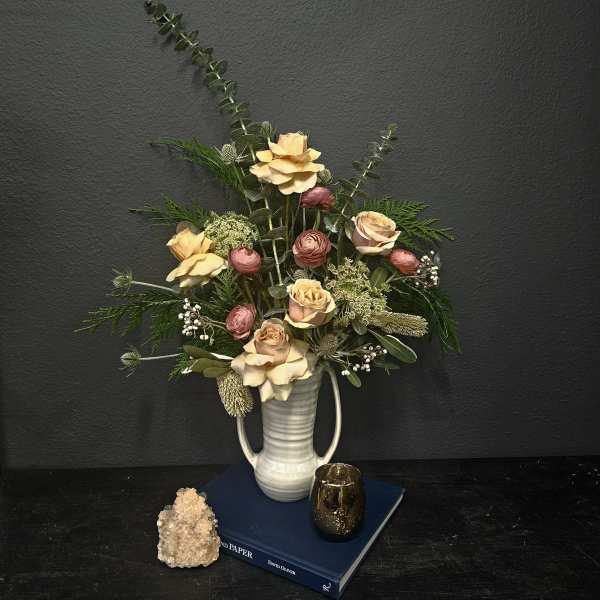 Arrangement of pale roses and pink ranunculus in a white vase