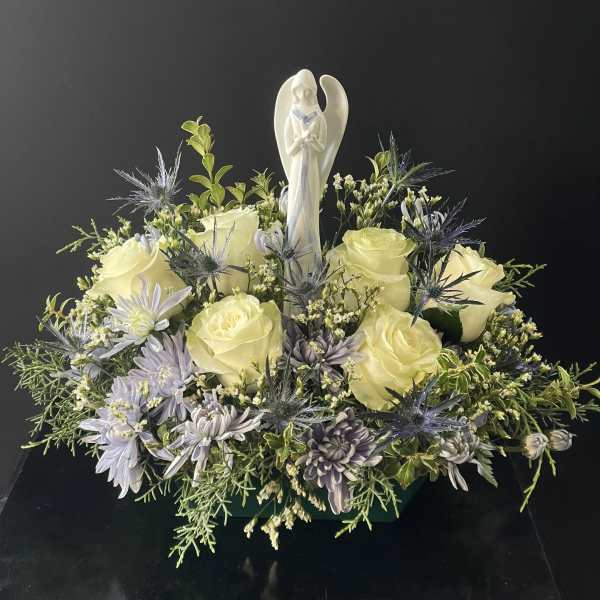 Cream roses and lavender flowers arranged around an angel figurine