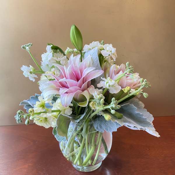 Pink lilies and white flowers in a clear glass vase
