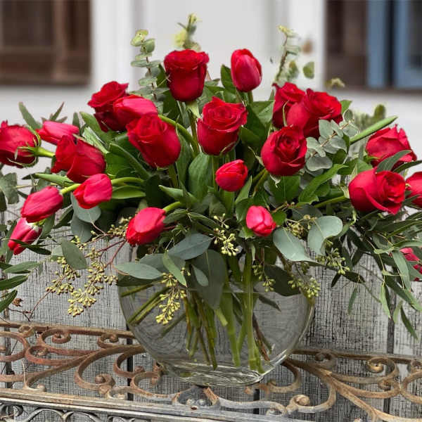 Red roses arranged in a clear glass vase with eucalyptus