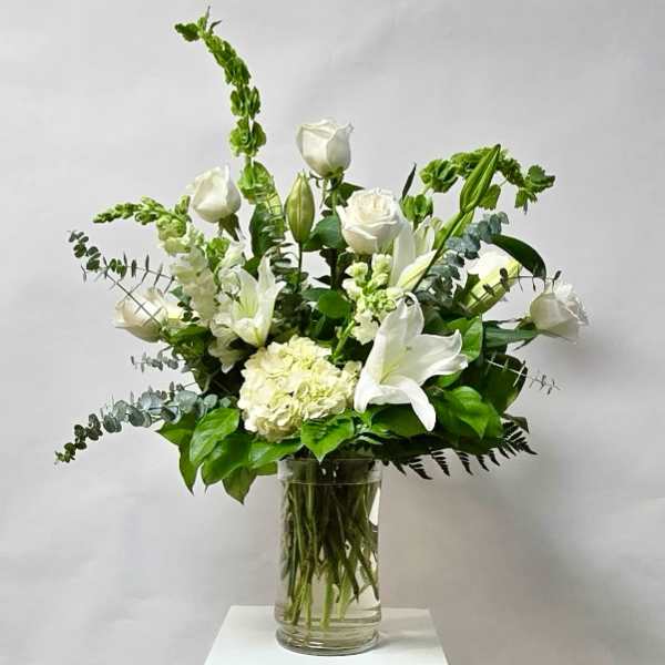 White roses and lilies arranged in a clear glass vase