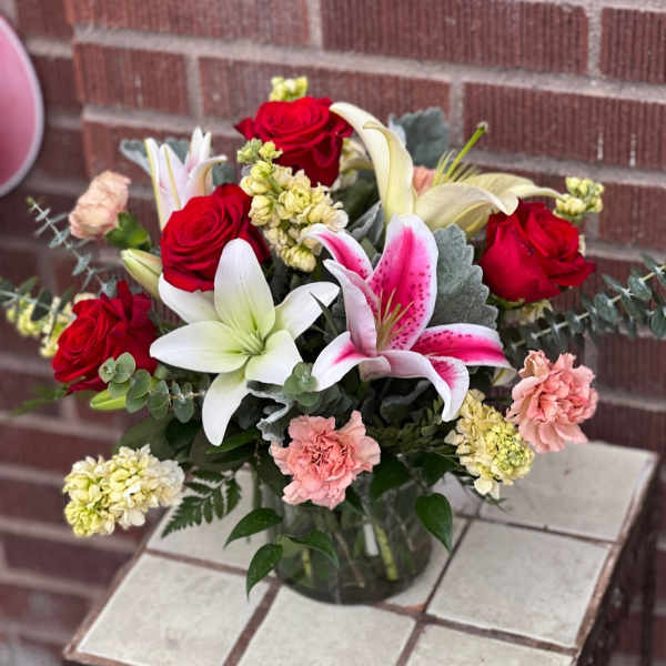 Bouquet of red roses, lilies, and pink carnations in a glass vase