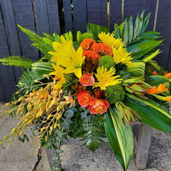 Bright tropical bouquet with yellow and orange flowers and lush greenery