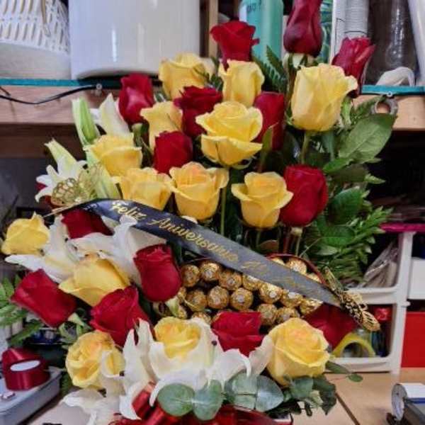 Bouquet of red and yellow roses in a white gift box with a red ribbon.