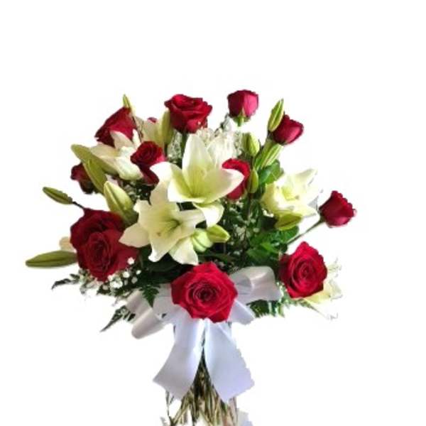 Red roses and white lilies in a clear vase with a white ribbon