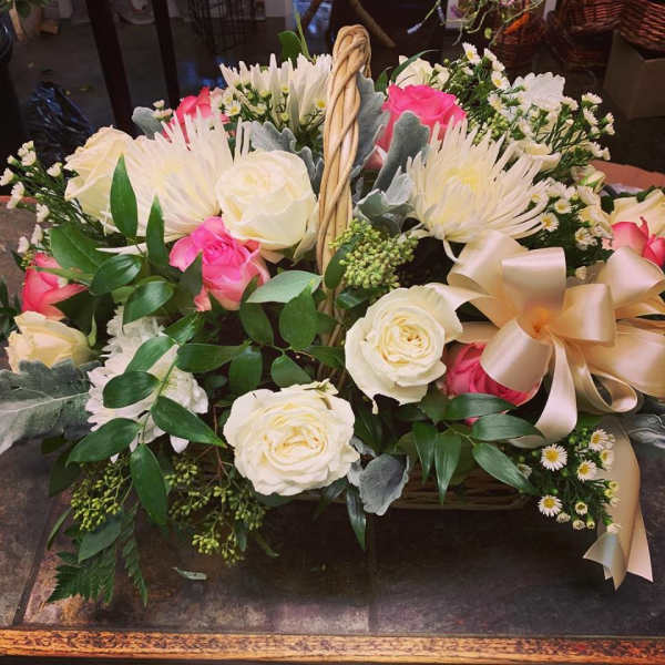 Basket arrangement of white and pink roses with a large satin bow