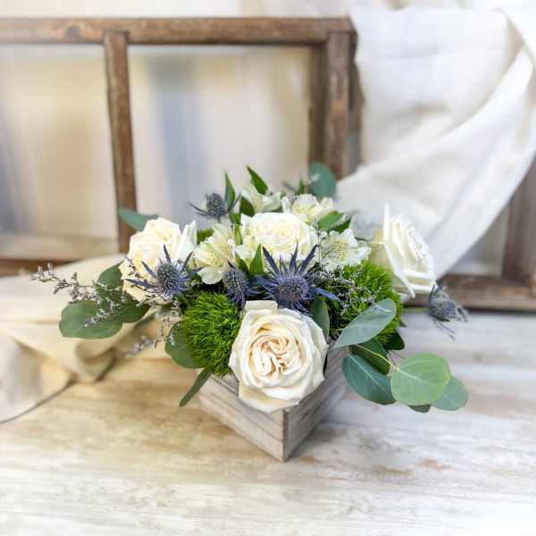 White roses and blue thistle in a wooden box