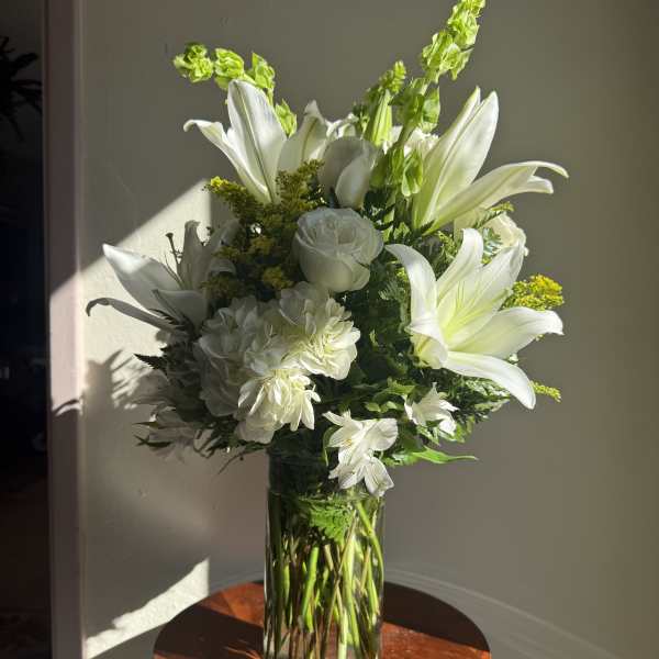White lilies and roses arranged in a clear glass vase