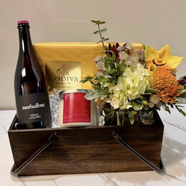 Gift basket with flowers, wine, chocolates, and a candle