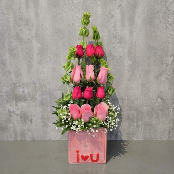 Tiered pink rose arrangement in a pink box with an "I love U" front decoration