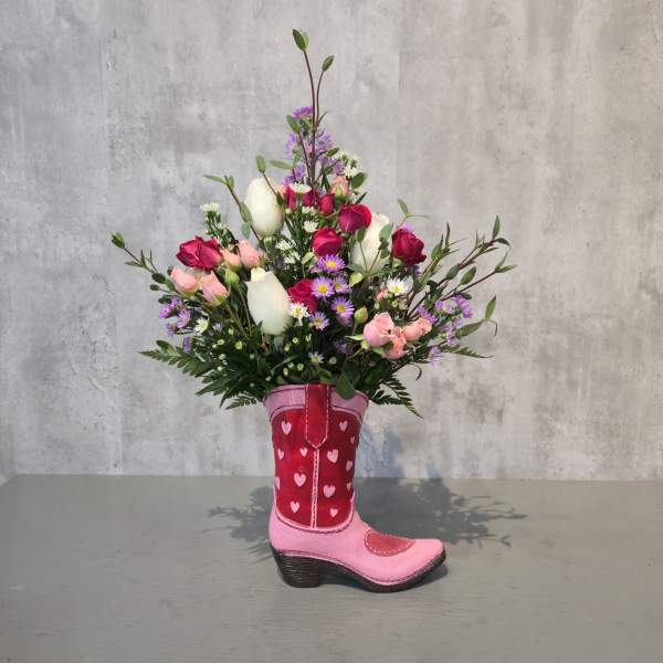 Bouquet of pink, white, and purple flowers arranged in a pink cowboy boot vase