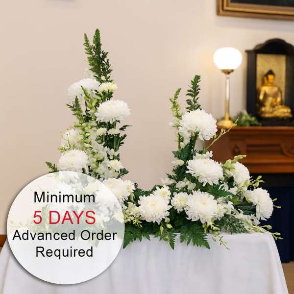 White chrysanthemum sympathy arrangement on a draped table in a ceremonial setting