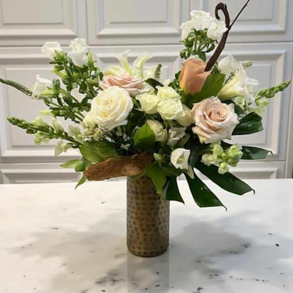 White and blush roses arranged in a tall patterned vase