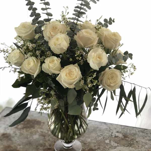 Cream rose bouquet in a clear glass vase with eucalyptus